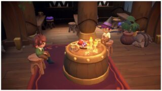 image from fae farm of a player sitting on stools at a wooden barrel table with the character argyle as they chat over a pint of drink and fruit, there are glowing candles on the table too as they sit inside the tavern