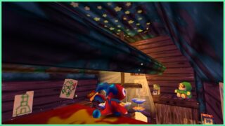 The image shows the Treehouse from the top of the parkour climb (I did it!). Across from Fynn, who has his back to the camera, you can see a plushie on the far side of the room on a separate shelf. Off to the left hung on the wooden walls are hand-drawn posters of a Yoshi-like green dragon outline