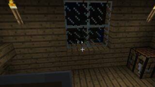 A screenshot from the wonderland.jar Minecraft mod. It shows a view from a player house at night, with a large, too-realistic eye peering over the window ledge, in towards the viewer.